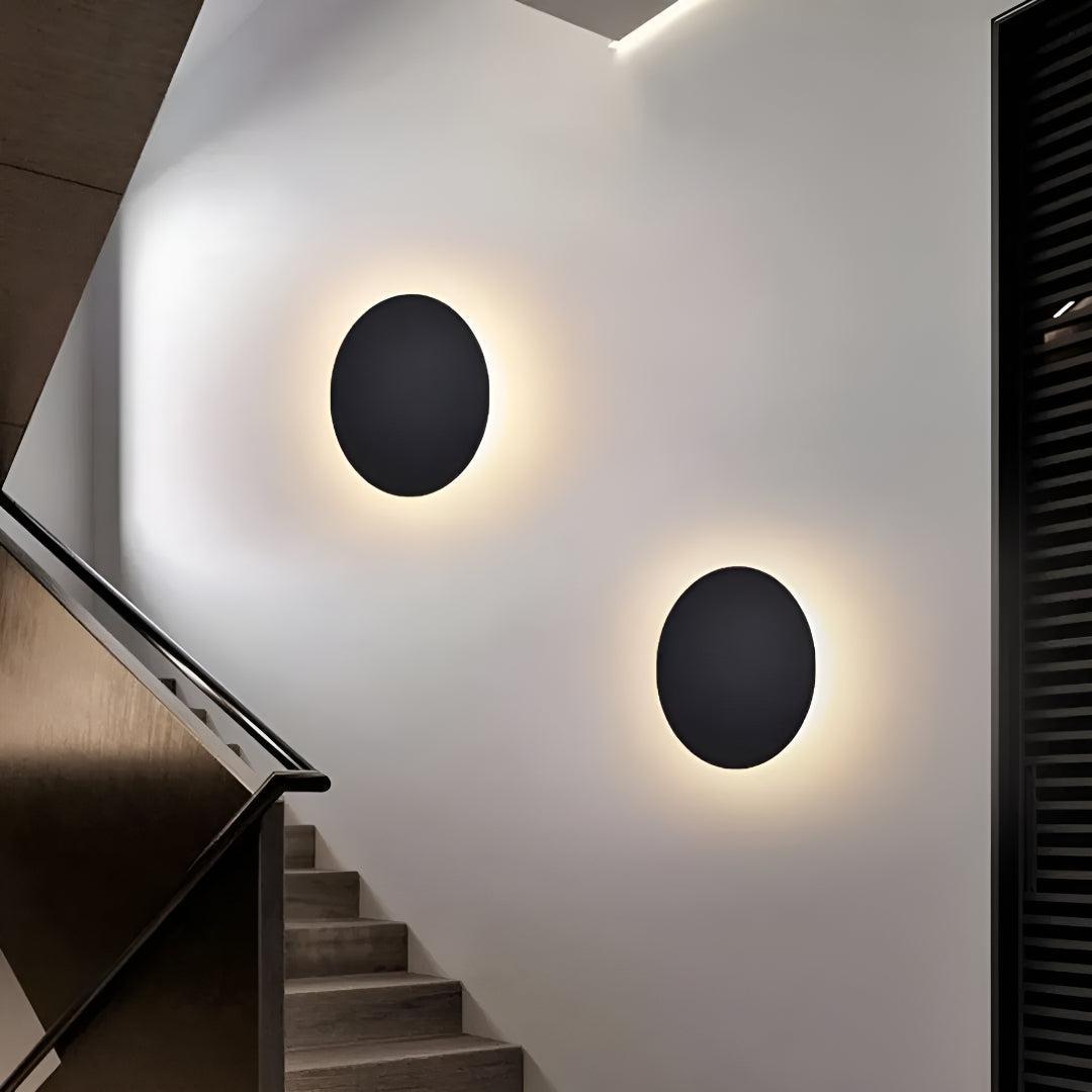 Two Round Metal LED wall sconces cast warm halos along a stairway.